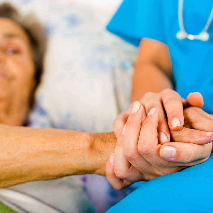 Social care provider holding senior hands in caring attitude - helping elderly people.