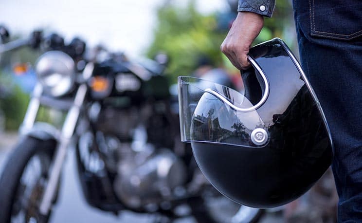 Motorcyclist holding helmet